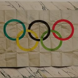A trompe-l'oeil painting by Lucy McKenzie of a marble surface upon which sits a paper picture of the Olympic rings, which has previously been folded into small sections